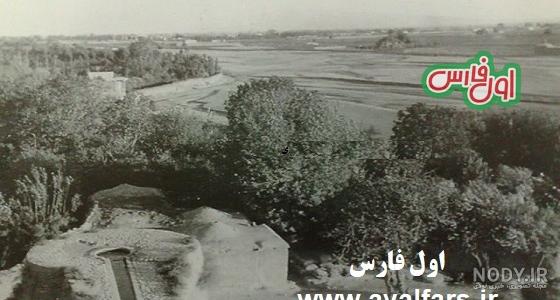 عکس آسیاب بادی قدیمی در کنار درخت های سبز در برابر آسمان آبی و ...