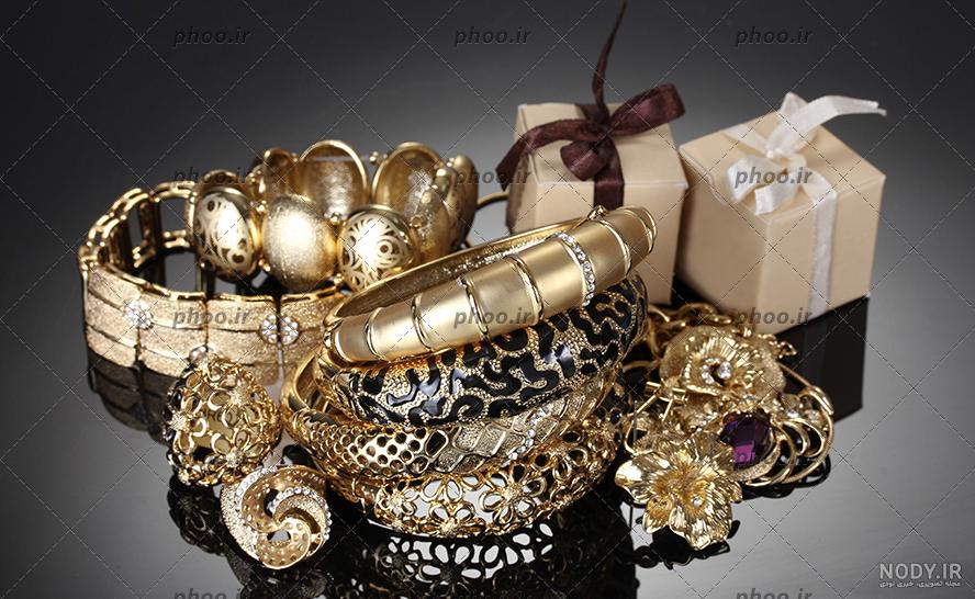عکس با کیفیت تبلیغاتی دو جعبه کادو طلایی که اطراف آن طلا و جواهرات ...