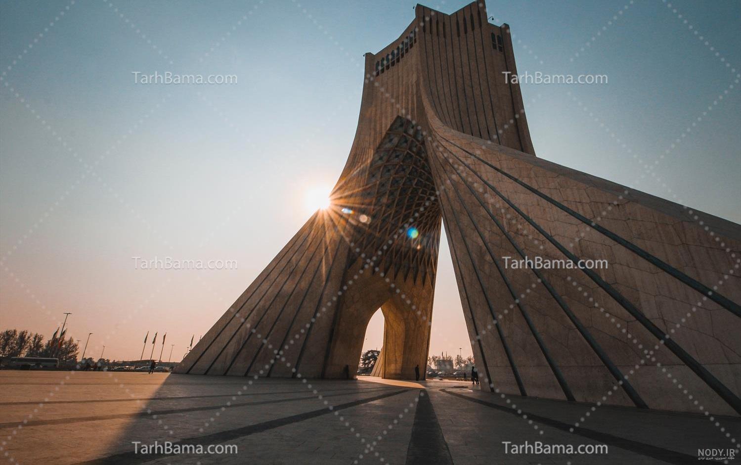 عکس برج آزادی نمای سنگ شده و آسمانی آبی و گل های نارنجی – عکس با کیفیت و تصاویر استوک حرفه ای عکس برج آزادی نمای سنگ شده و آسمانی آبی و گل های نارنجی – عکس با کیفیت و تصاویر استوک حرفه ای